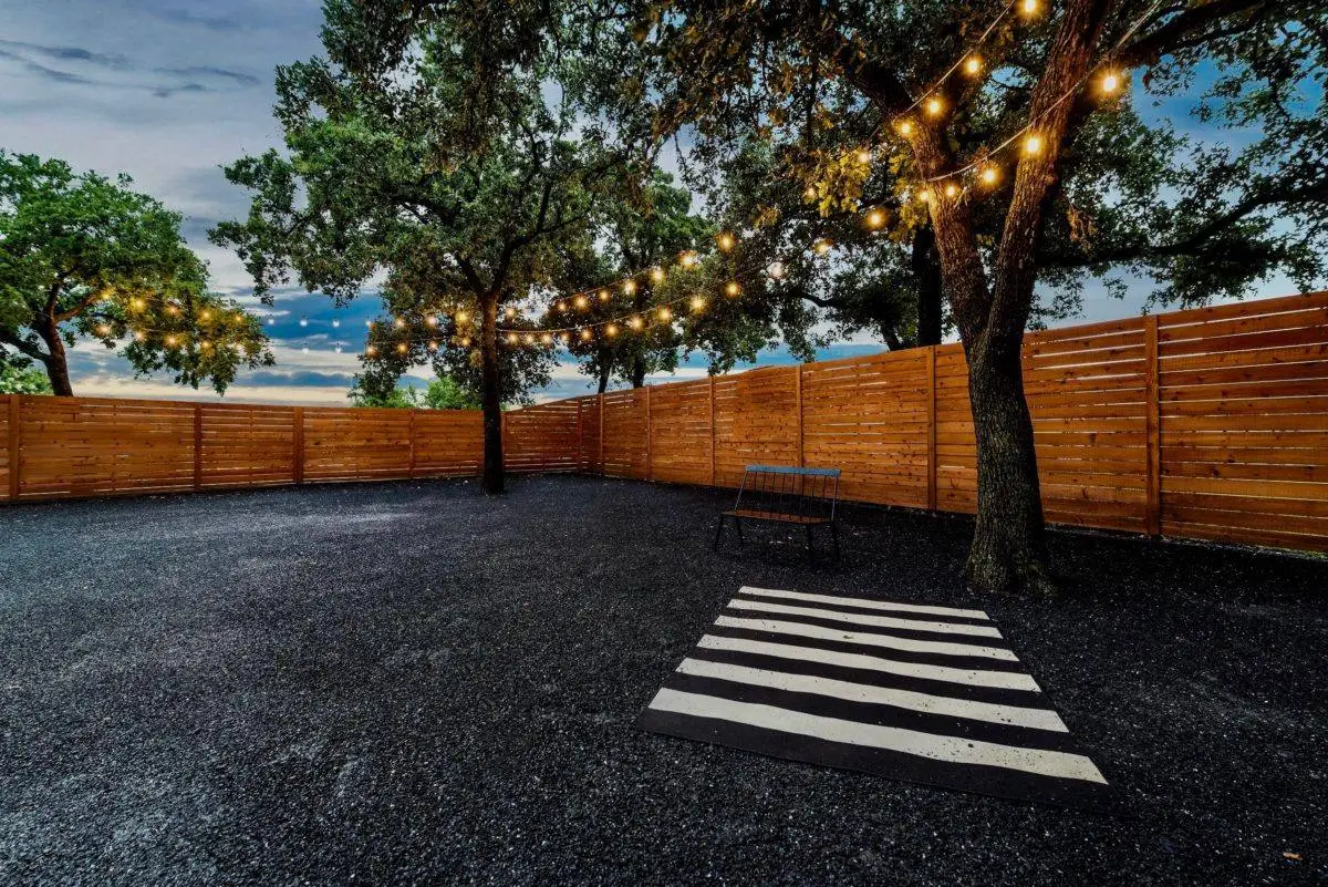Backyard with string lights strung through mature trees at dusk